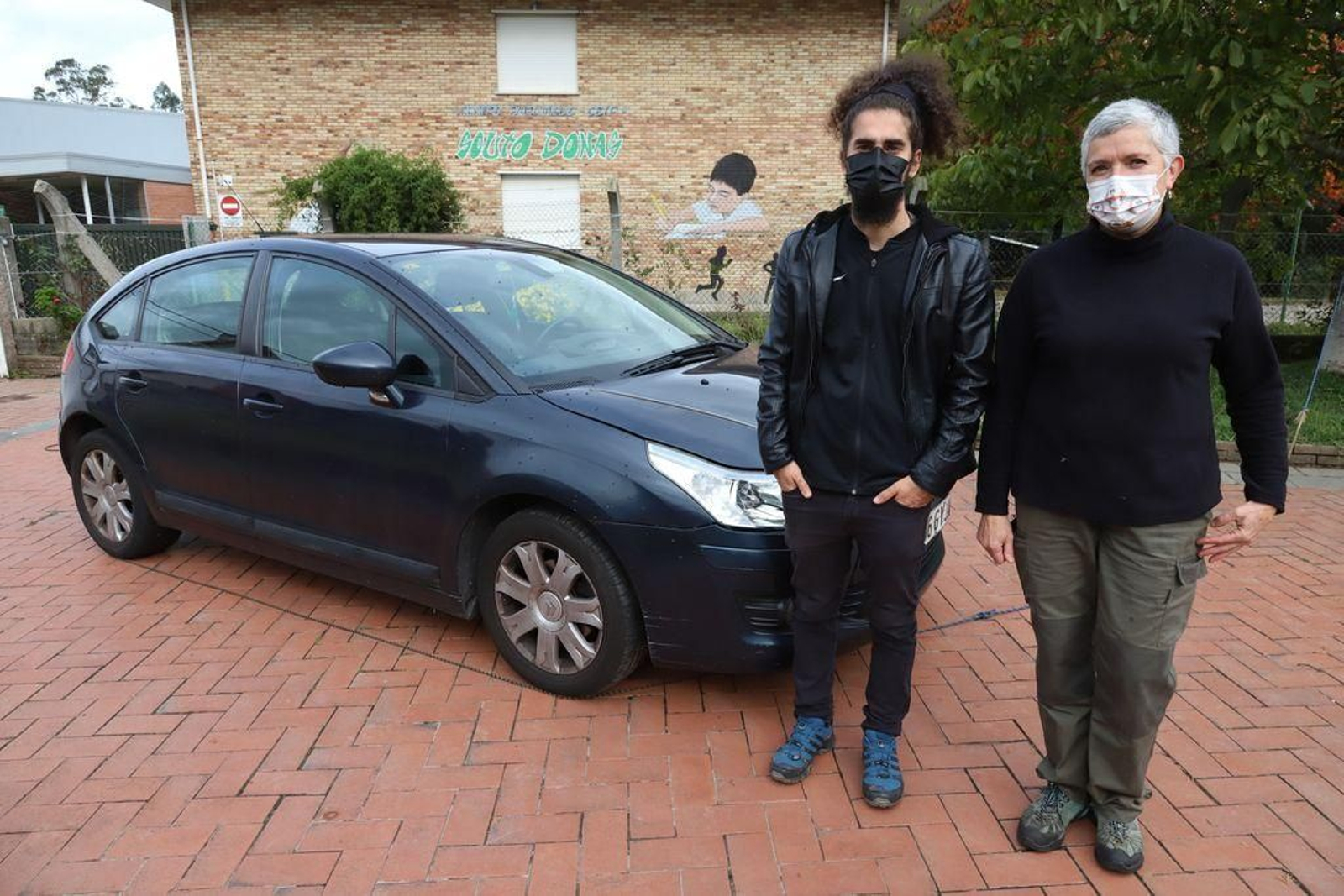 Los vecinos Xosé Lois y Teresa Pereira, en el patio de la vivienda ubicada a escasos metros de la escuela. Las moscas plagan ventanas, fachadas y cornisas.