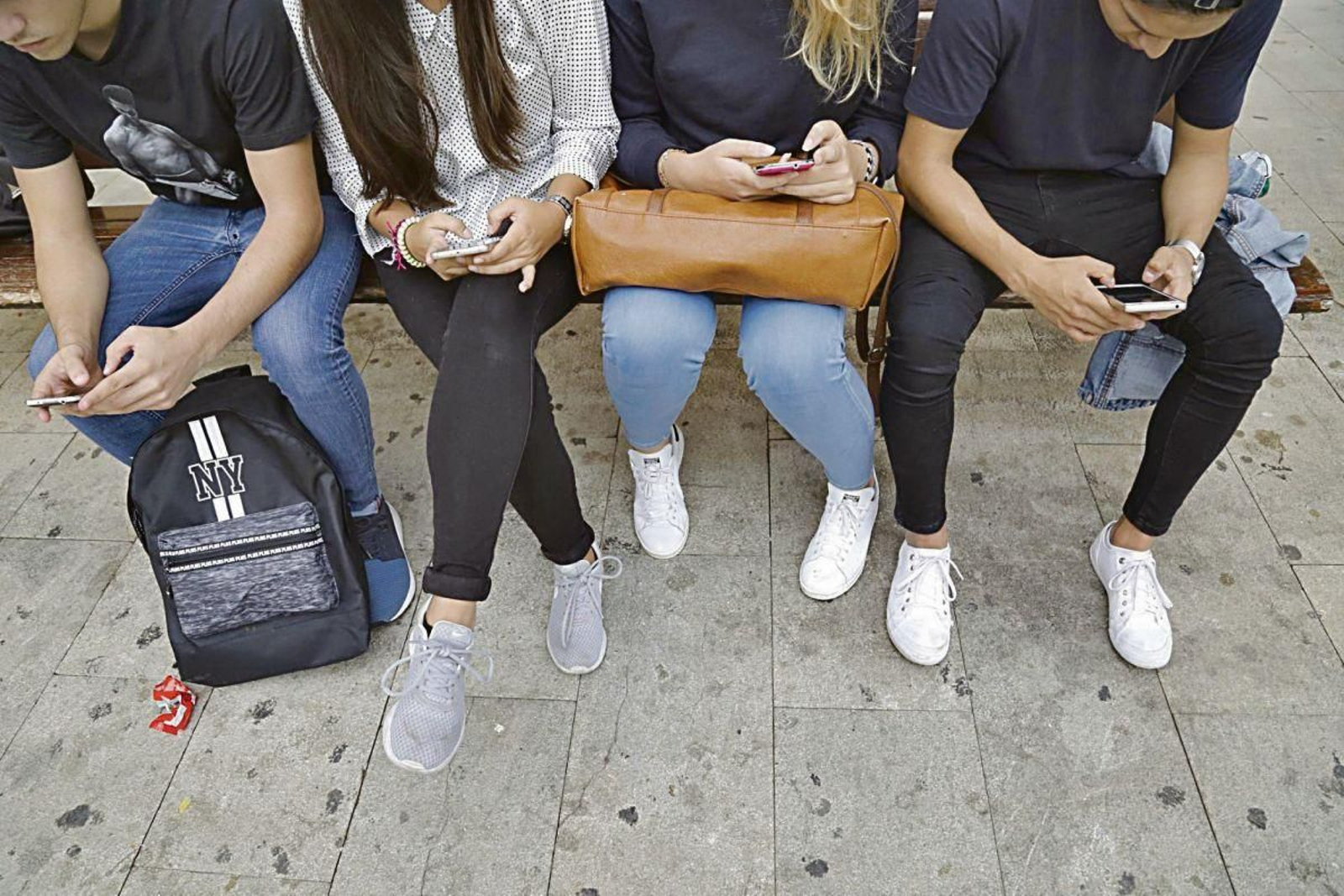 Tres jóvenes consultan su móvil.