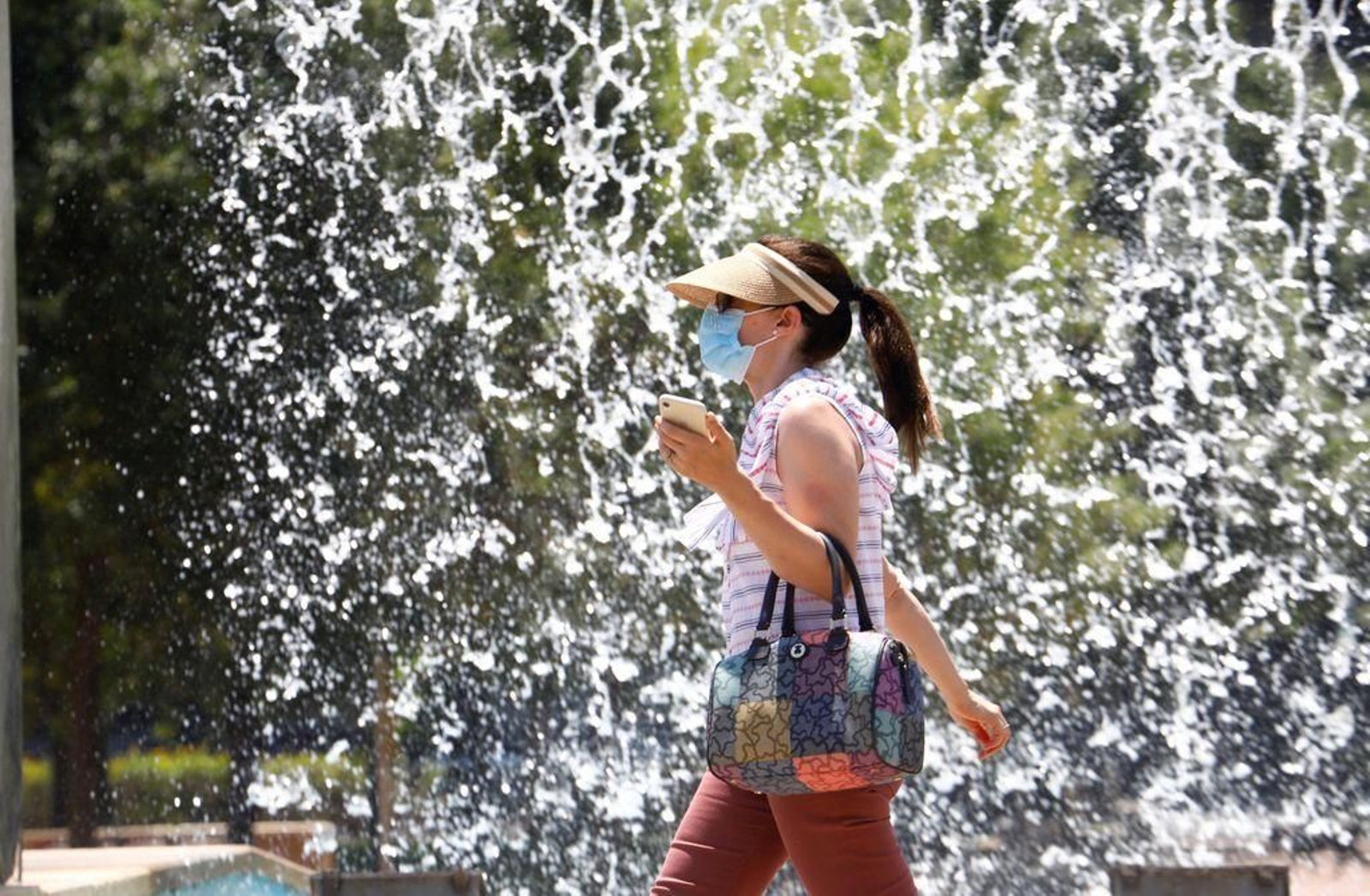 Una mujer protegida con mascarilla y visera pasea por Córdoba.