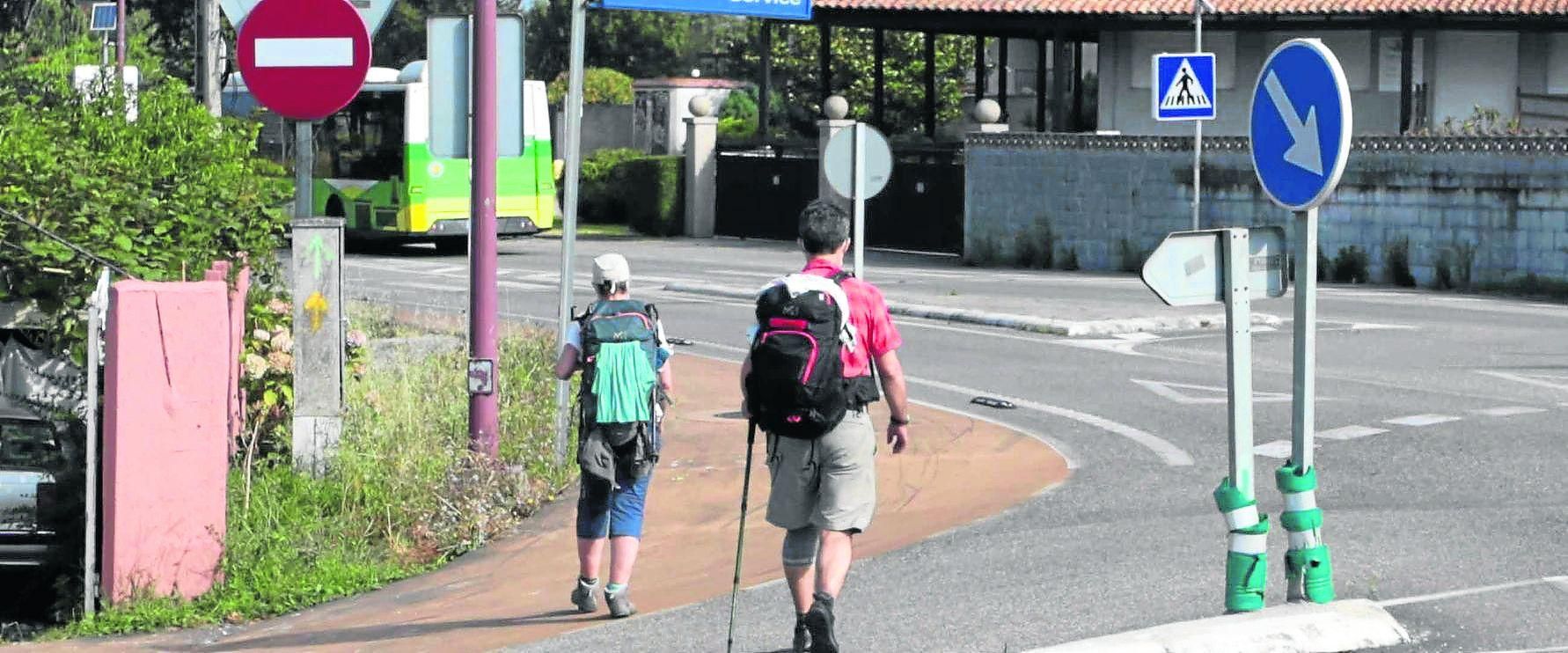 Una pareja de peregrinos, durante su marcha hacia Santiago en la carretera que transcurre entre Oia y Baiona