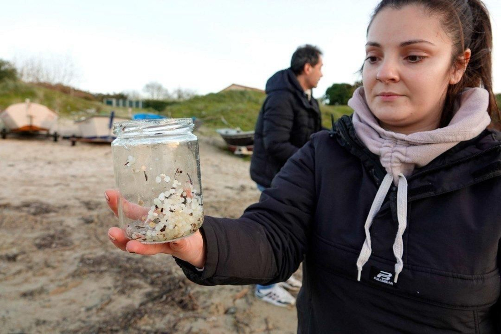 Voluntarios recogen pellets de plástico.