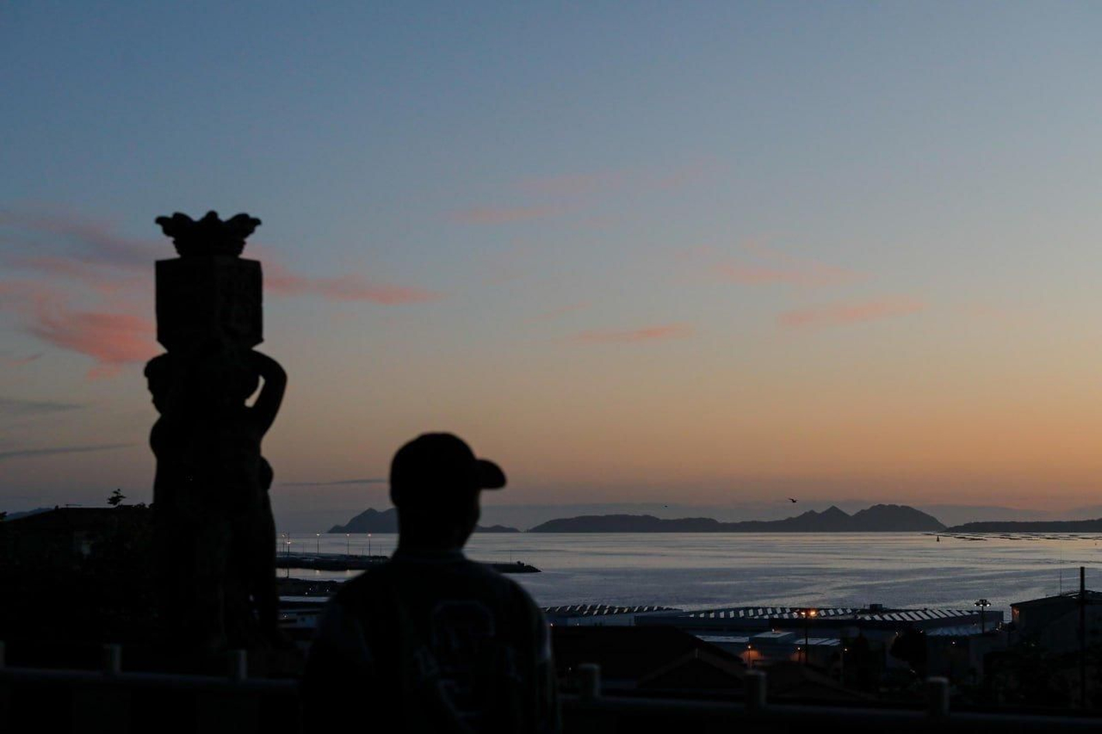 Un hombre contempla el atardecer en Vigo con las islas Cíes al fondo. // Jorge Santomé