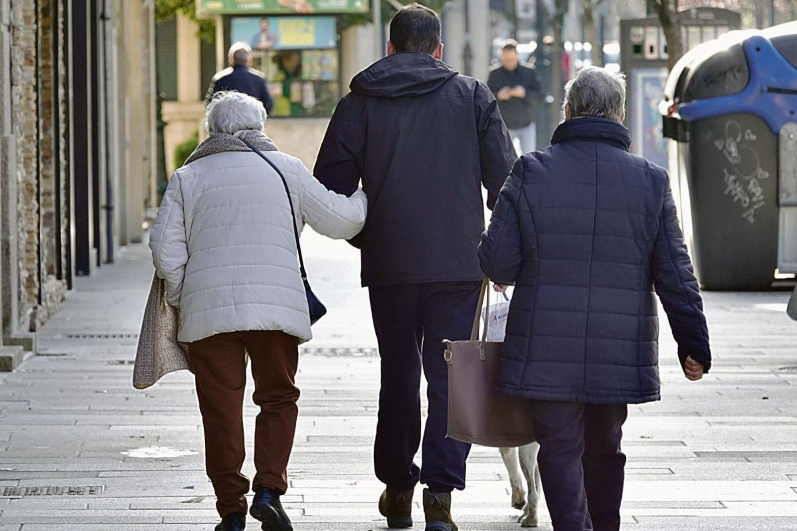 Una señora jubilada es acompañada por las calles viguesas del brazo de un adulto.