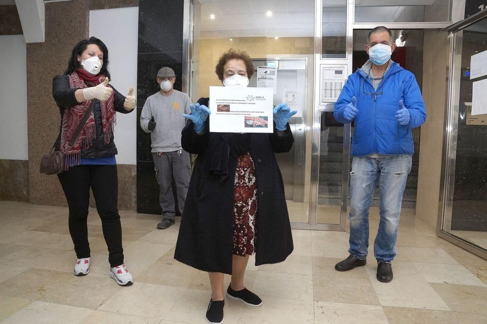Vecinos de la comunidad Boavista, ayer en el portal con el cartel de "orgullo por los sanitarios".
