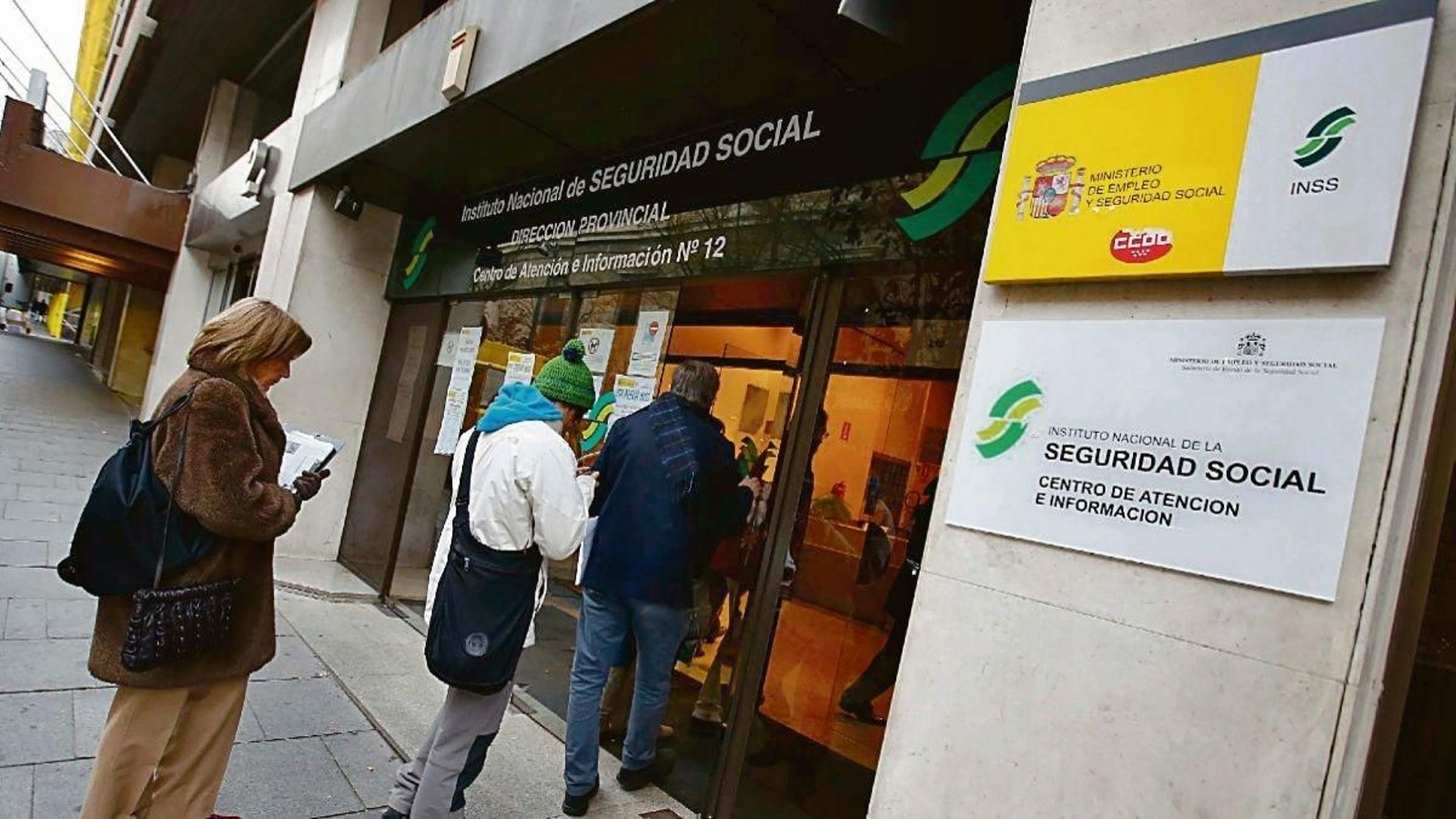 Varias personas realizan cola para acceder a una oficina de la Seguridad Social.