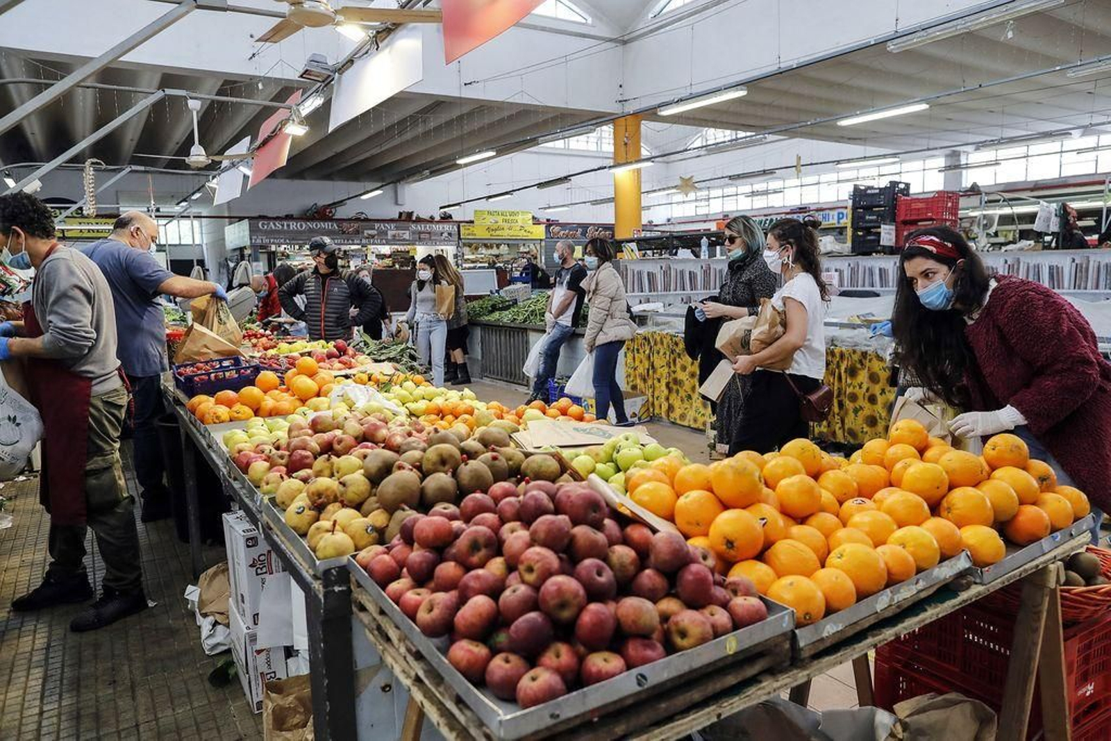 Personas comprando frutas en un supermercado.