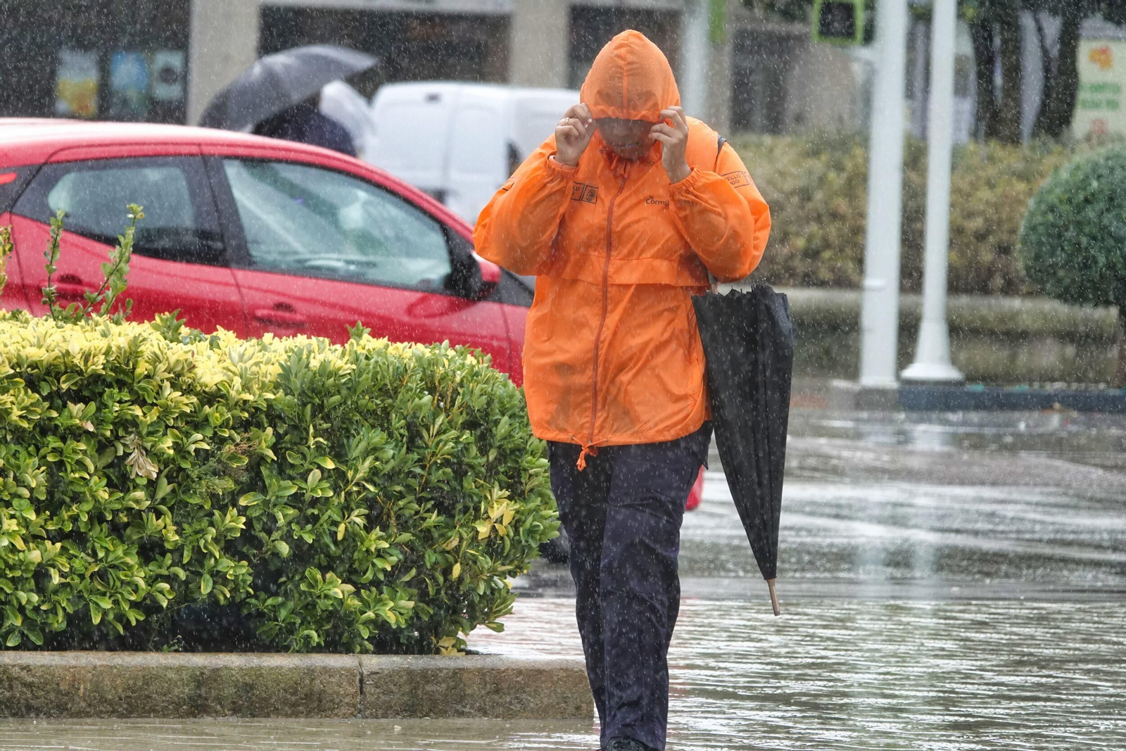 Una persona se protege de la lluvia en Vigo con su chubasquero sin hacer uso del paraguas.