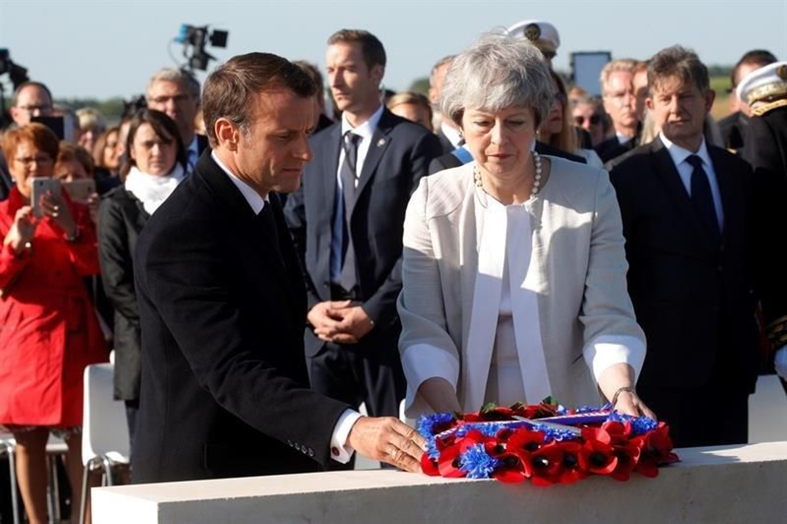El presidente galo, Emmanuel Macron (i), y la primera ministra, Theresa May (c), realizan una ofrenda floral durante la colocación de la primera piedra del monumento británico.