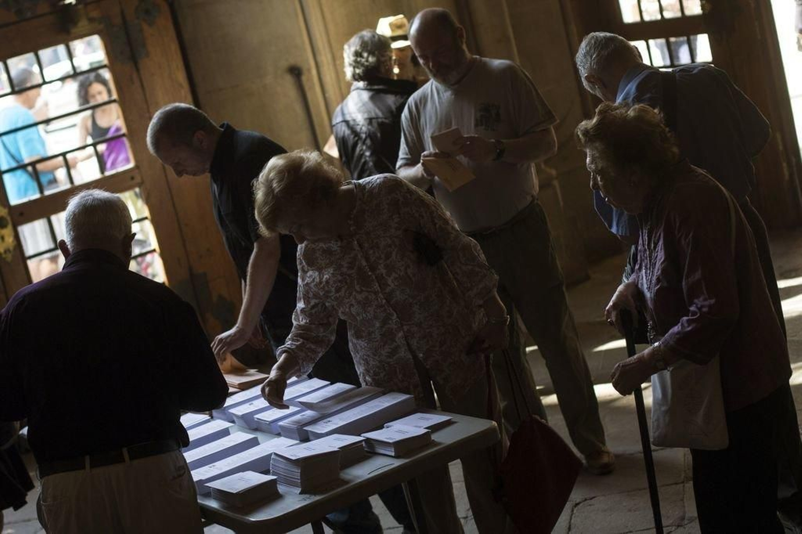 Un grupo de ciudadanos elige sus papeletas en un colegio electoral.