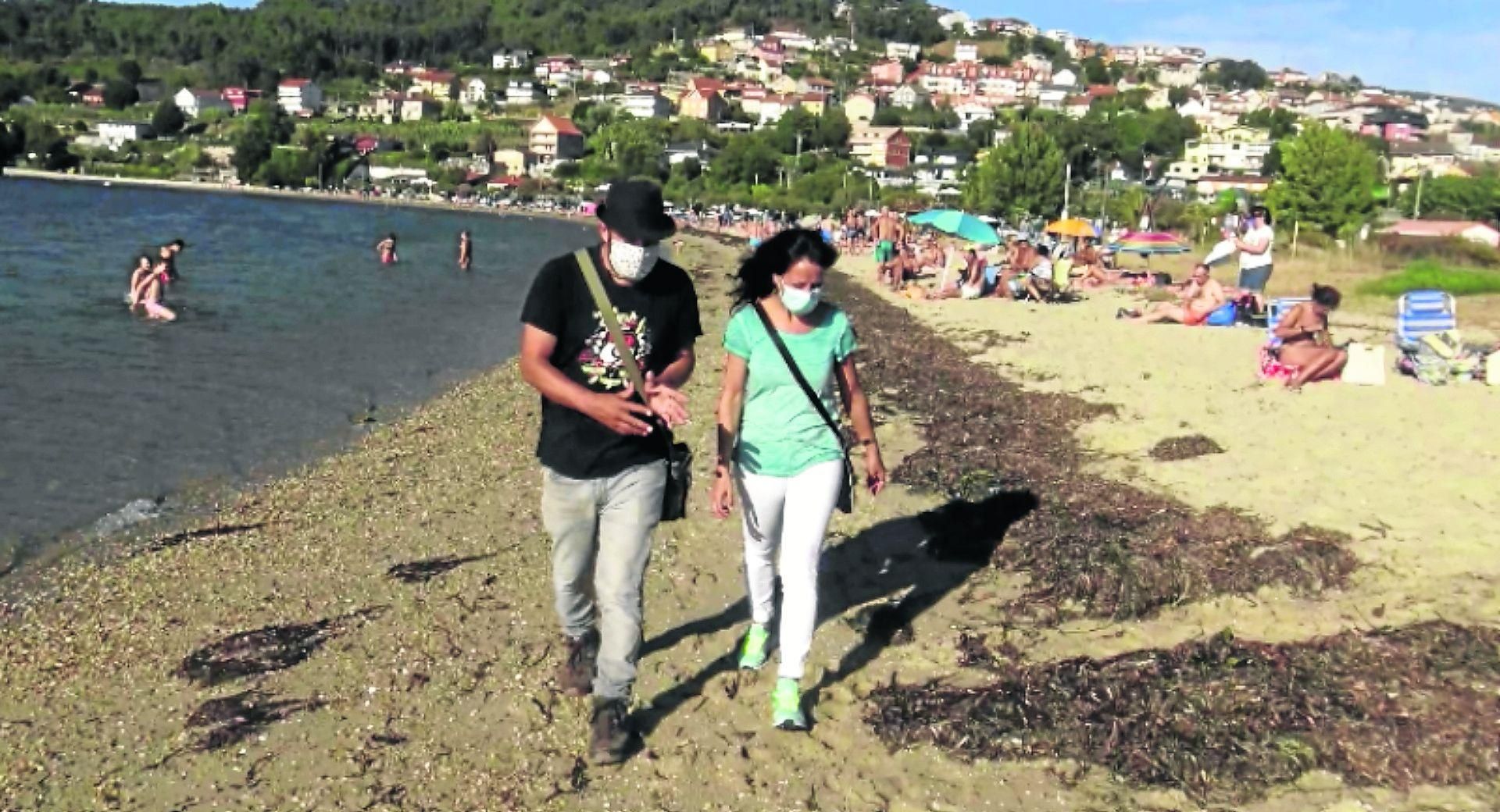 Roberto Villar y la bióloga de Ecoloxistas en Acción recorriendo la playa de Cesantes que cuenta ya con la "barrera" natural que crean las algas.