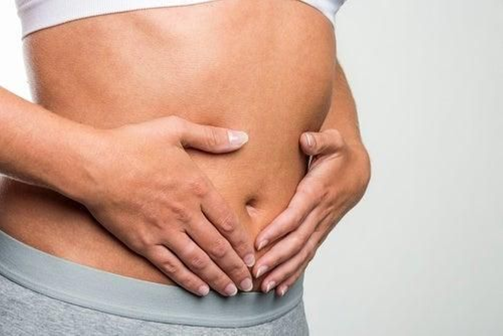 Una mujer echa la mano a la zona intestinal.