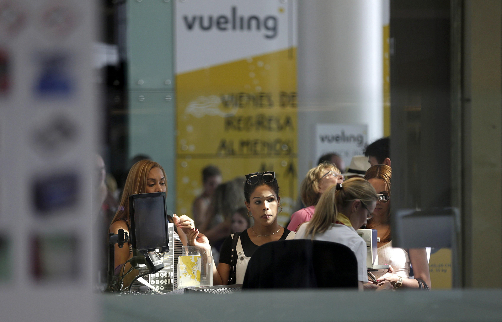 Personal de facturación de Vueling atiende a viajeros en el aeropuerto de El Prat.
