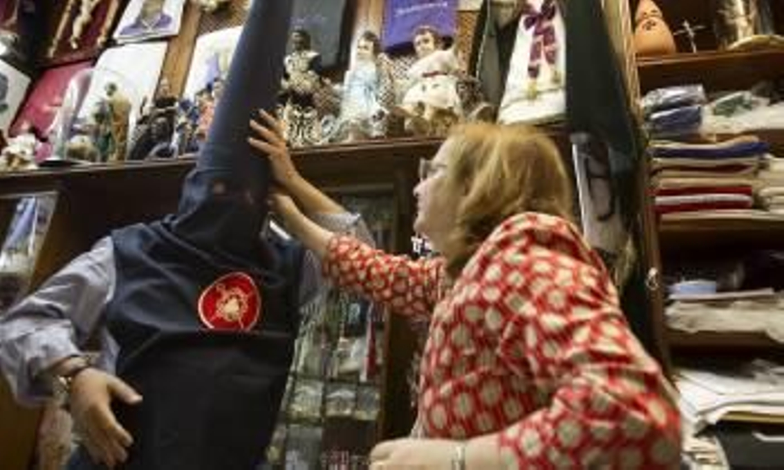 Un nazareno se prueba un capirote en una tienda sevillana. (Foto: J. M. VIDAL)