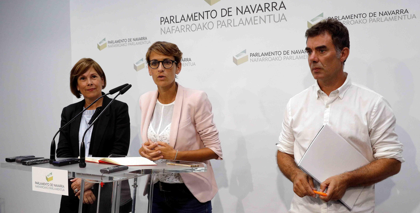 La presidenta del Gobierno de Navarra, María Chivite (c), junto a Uxue Barkos (d), y el consejero de Políticas Migratorias y Justicia, Eduardo Santos (i). EFE/Villar López