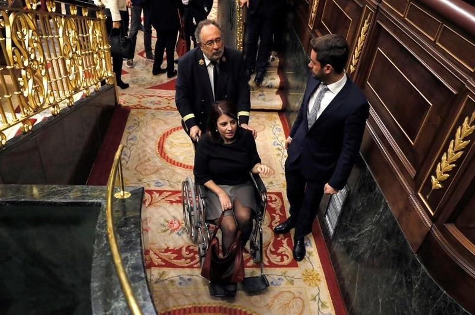 Adriana Lastra es trasladada en silla de ruedas por un ujier del Congreso  tras su torcedura de tobillo.