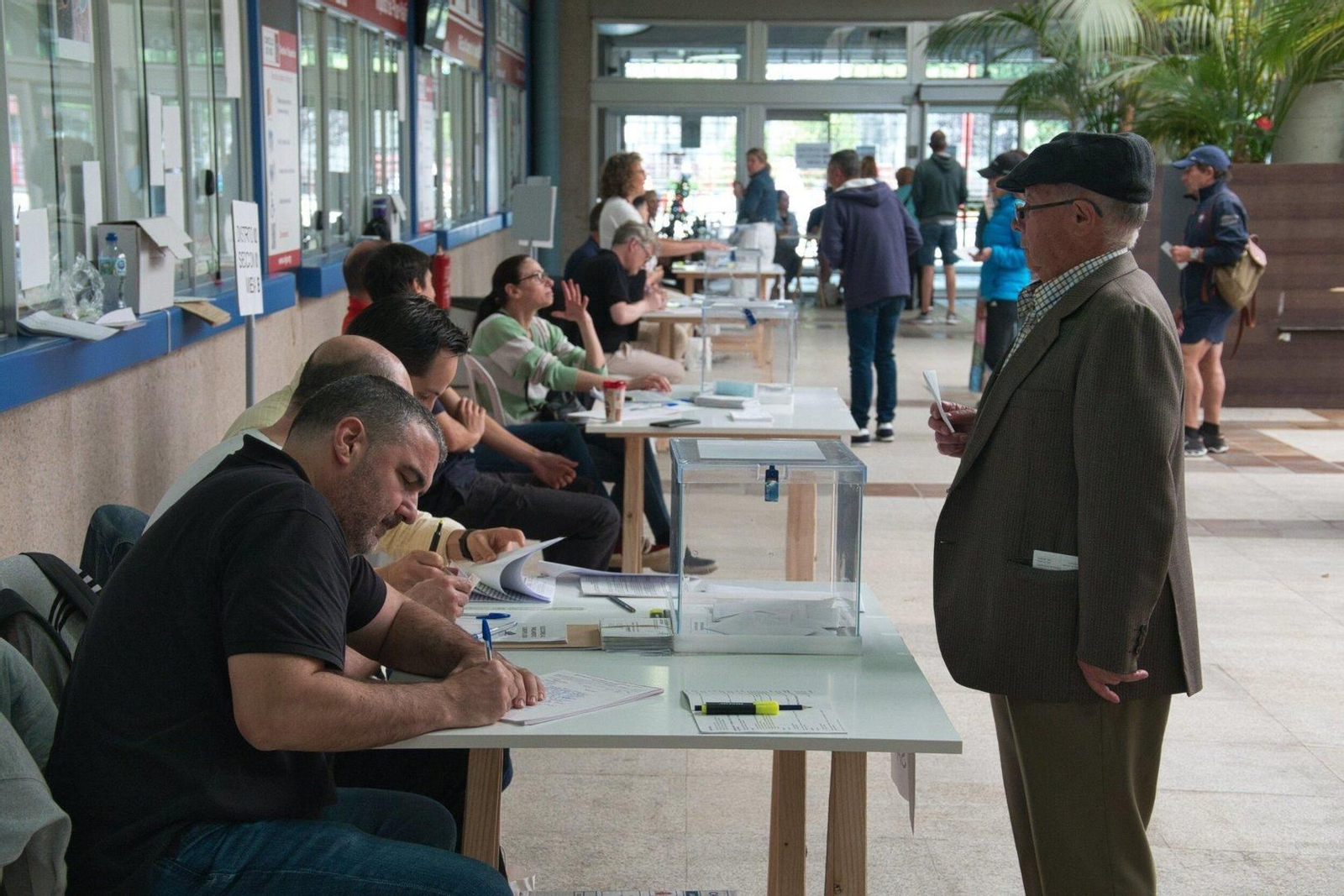 Un hombre espera a que comprueben sus datos para poder votar.