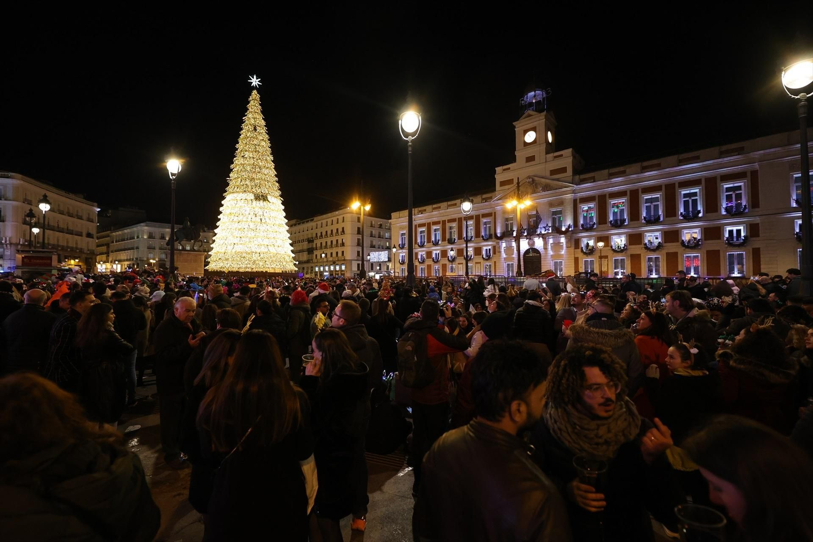 La Puerta del Sol madrileña repleta de personas con las uvas en la mano, a la espera de que suenen las campanadas.