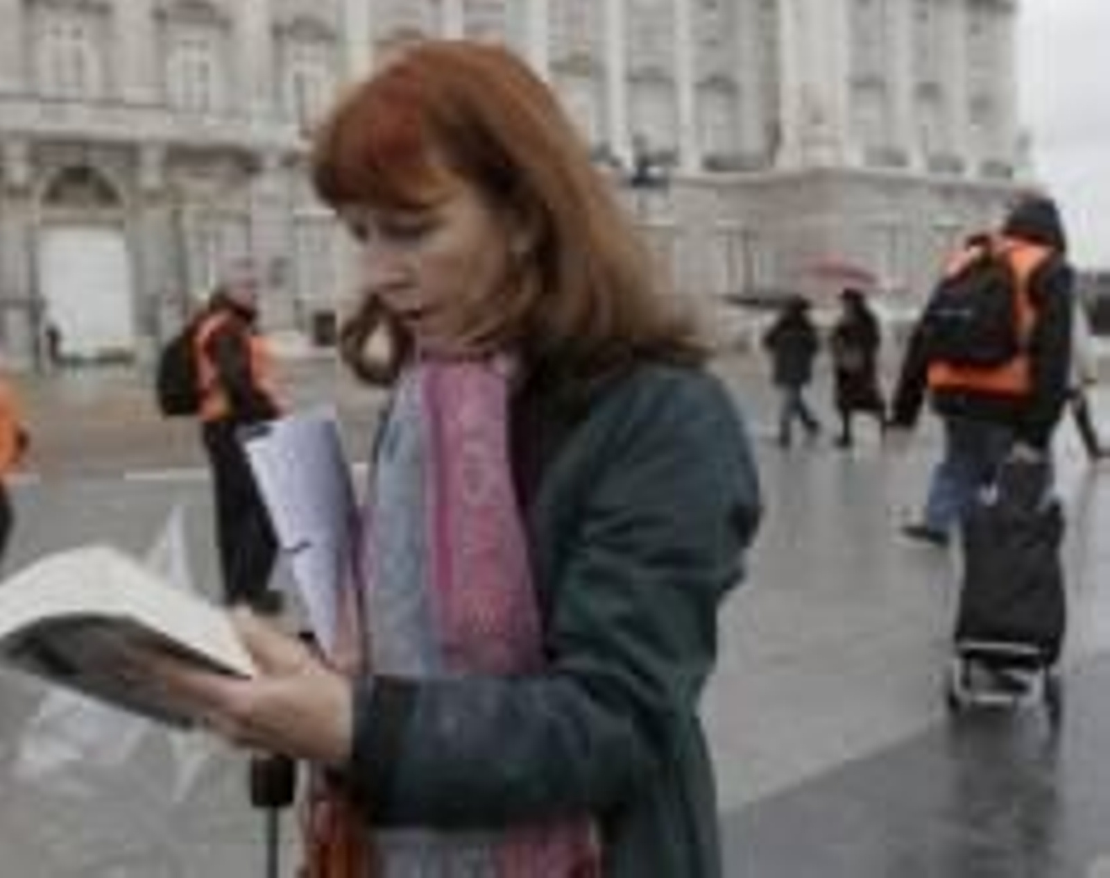 Una mujer leyendo por la calle mientras camina.