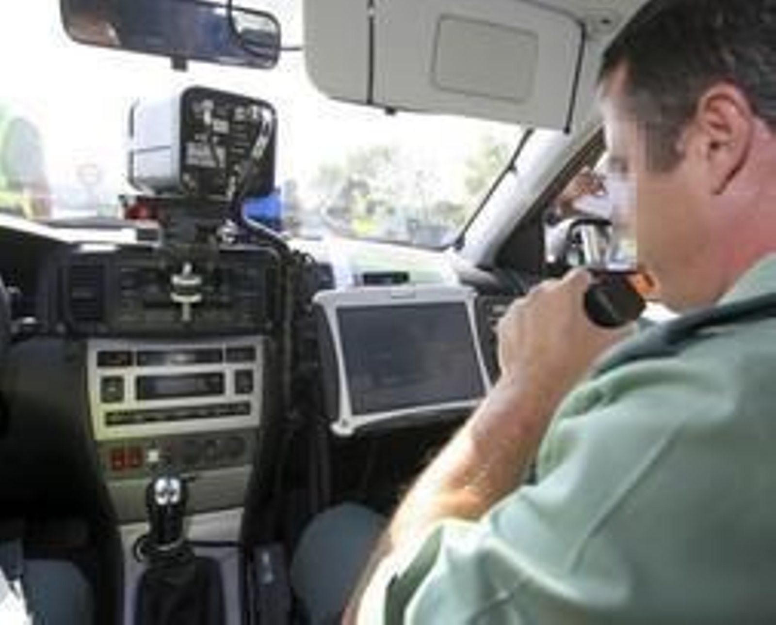 Un agente con un radar en el interior del coche patrulla.