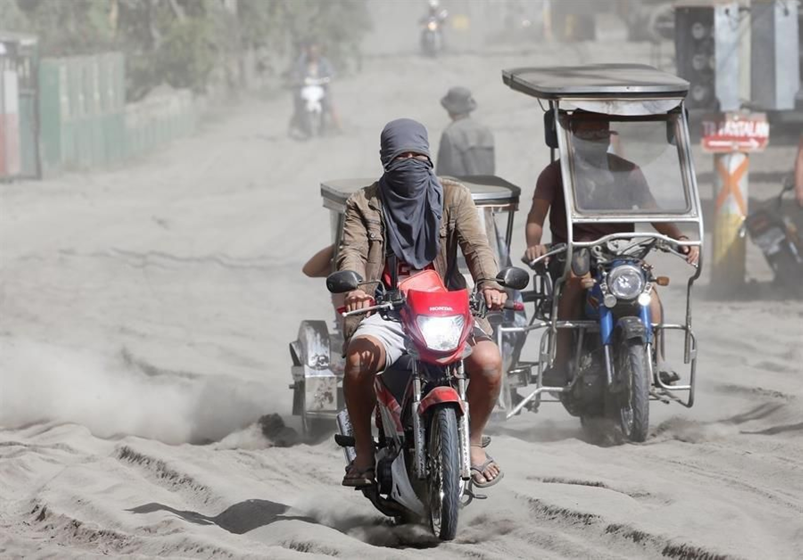 Dos motoristas recorren una carretera cubierta de ceniza, un día después de la erupción del volcán.