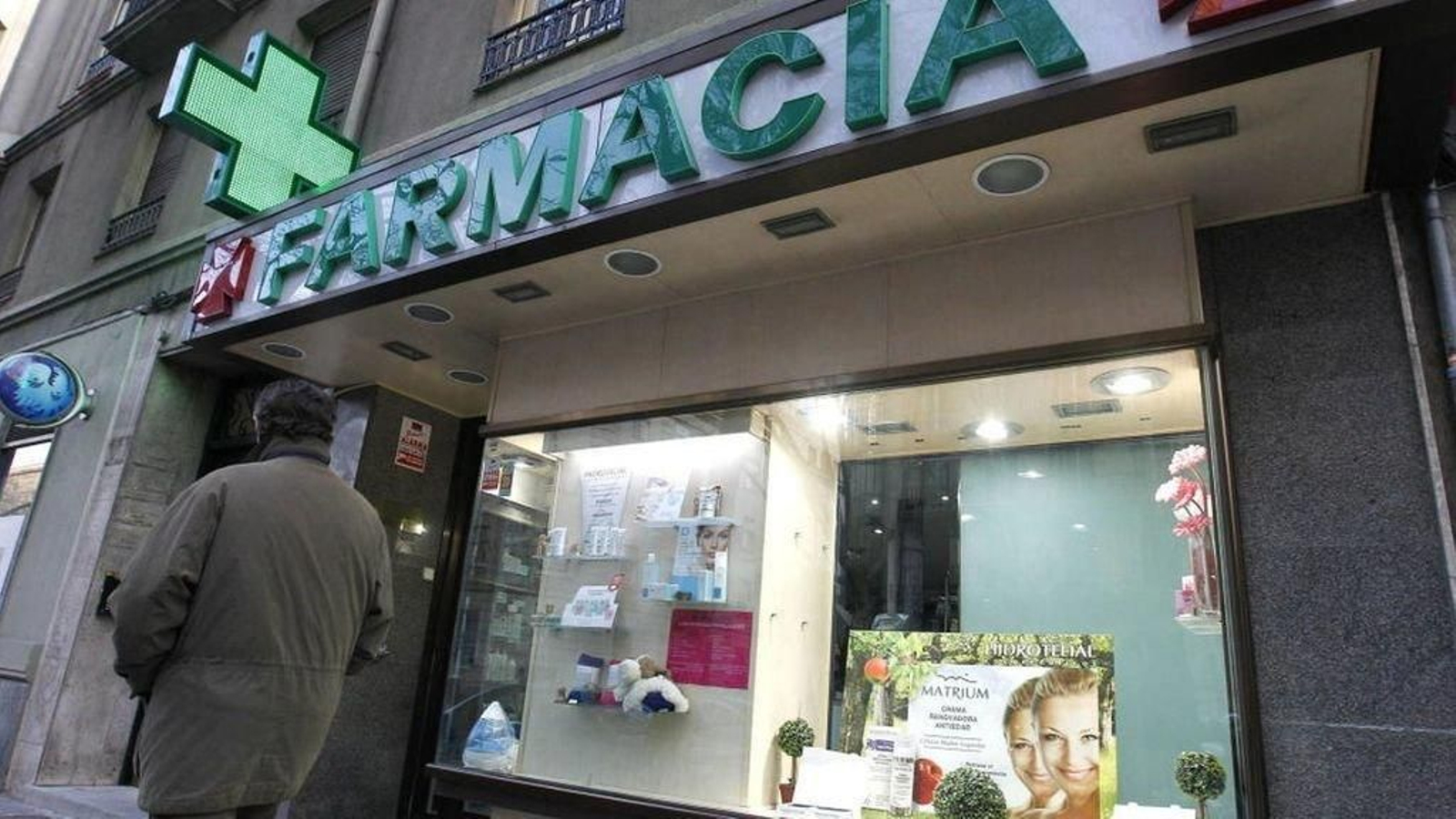 Un hombre pasa ante el escaparate de una farmacia.