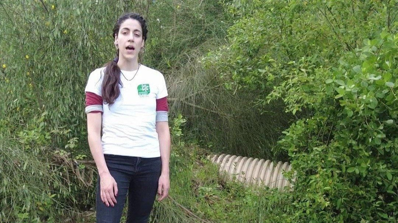 Elena Álvarez, de Ecoloxistas en Acción, ante el emisario que sale de la Ciudad deportiva del Celta y que, según han denunciado, vierte aguas fecales cerca de las traídas de aguas vecinales de Mos.