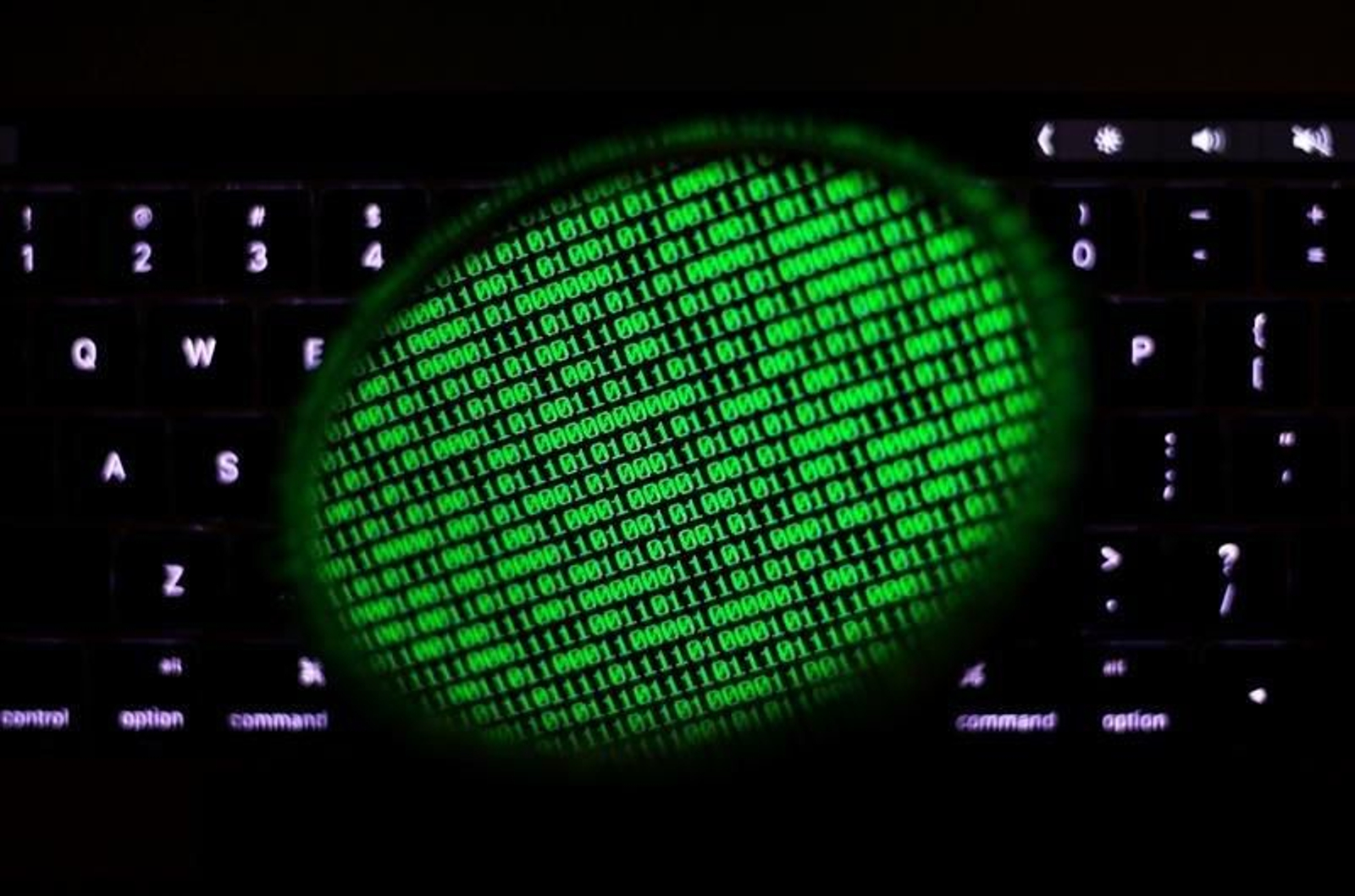 Un espejo refleja una pantalla de ordenador que muestra un código binario