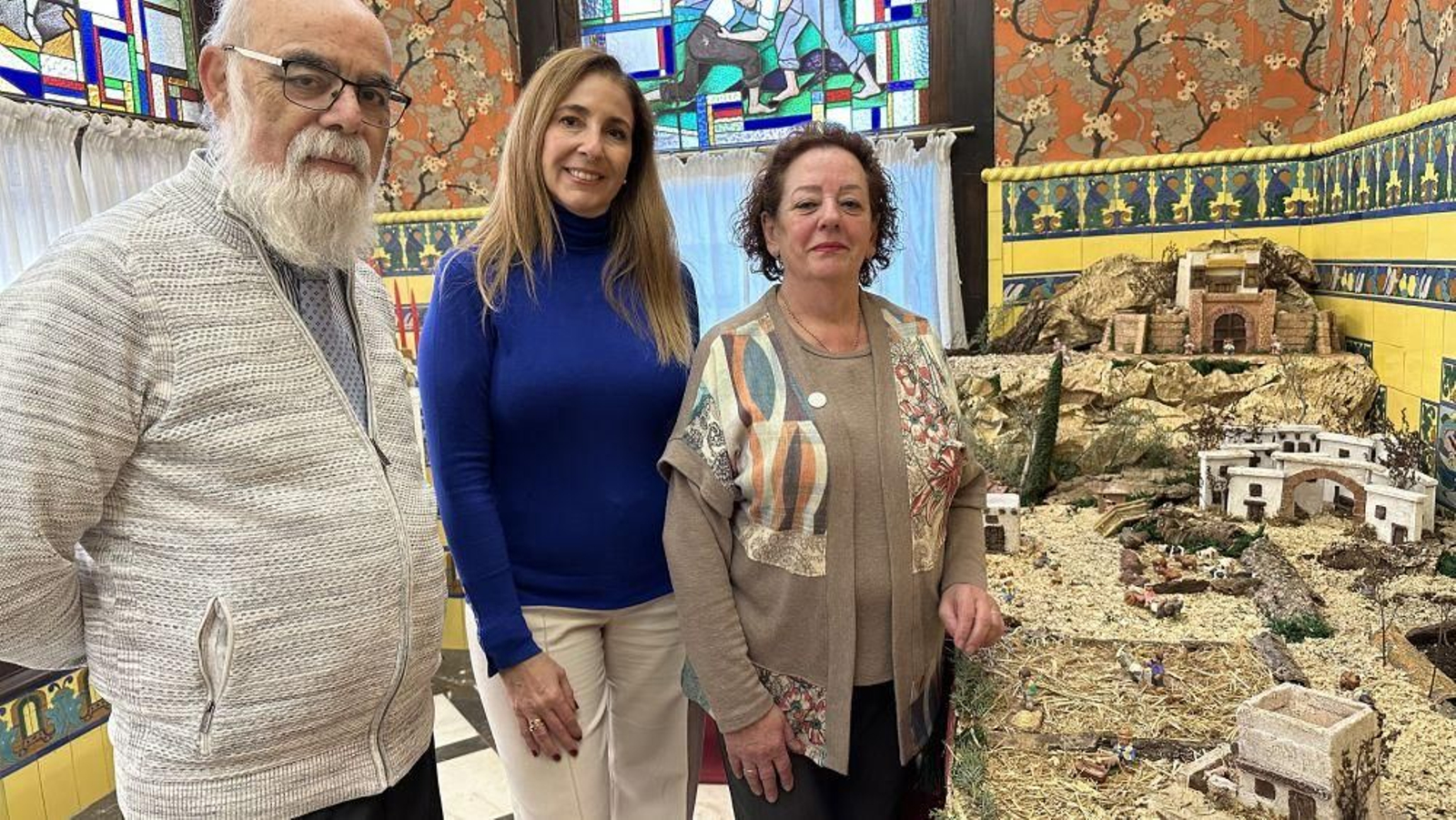 La directora del Museo de la Emigración de León, junto a miembros de la Asociación Belenista, junto al Nacimiento.