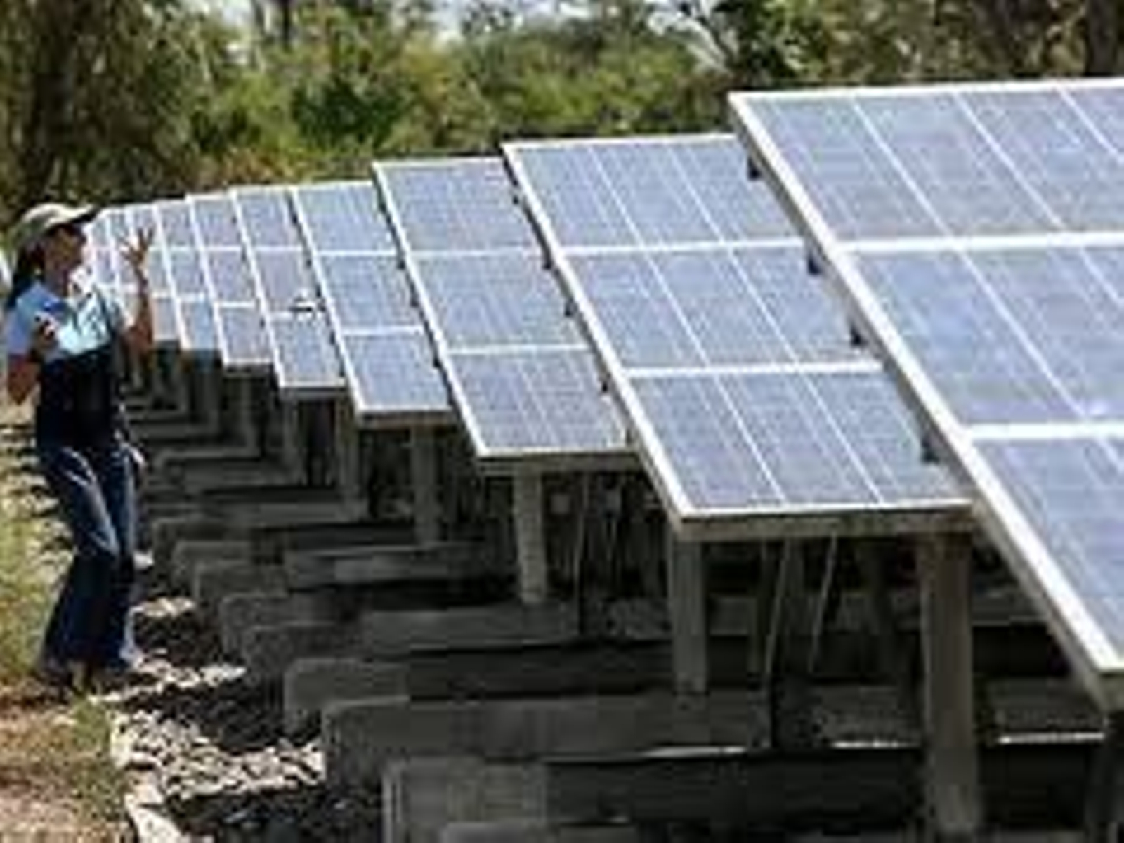 Una trabajadora al lado de varios paneles solares.