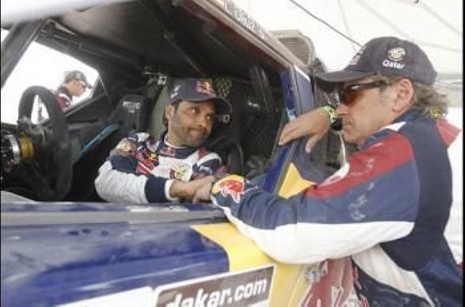 El piloto catarí Nasser Al-Attiyah (i) habla con su compañero el español Carlos Sainz (d)