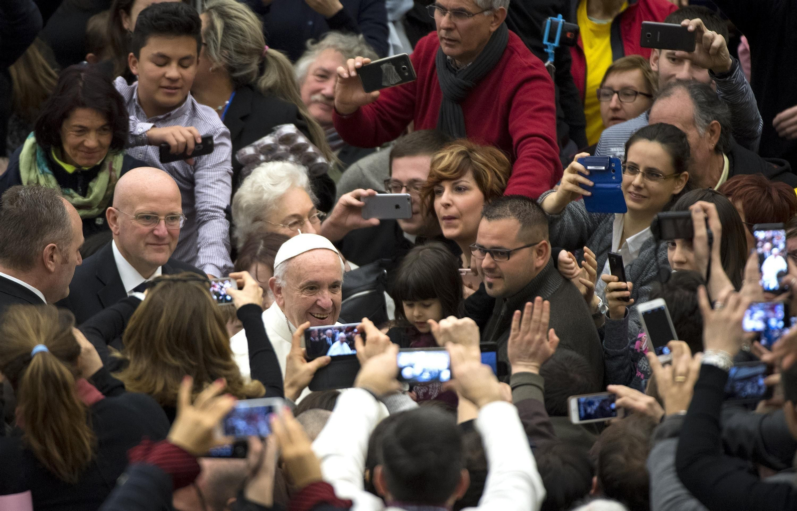 El papa Francisco sonríe y saluda a los fieles que le rodean y le hacen fotografías en el Vaticano.