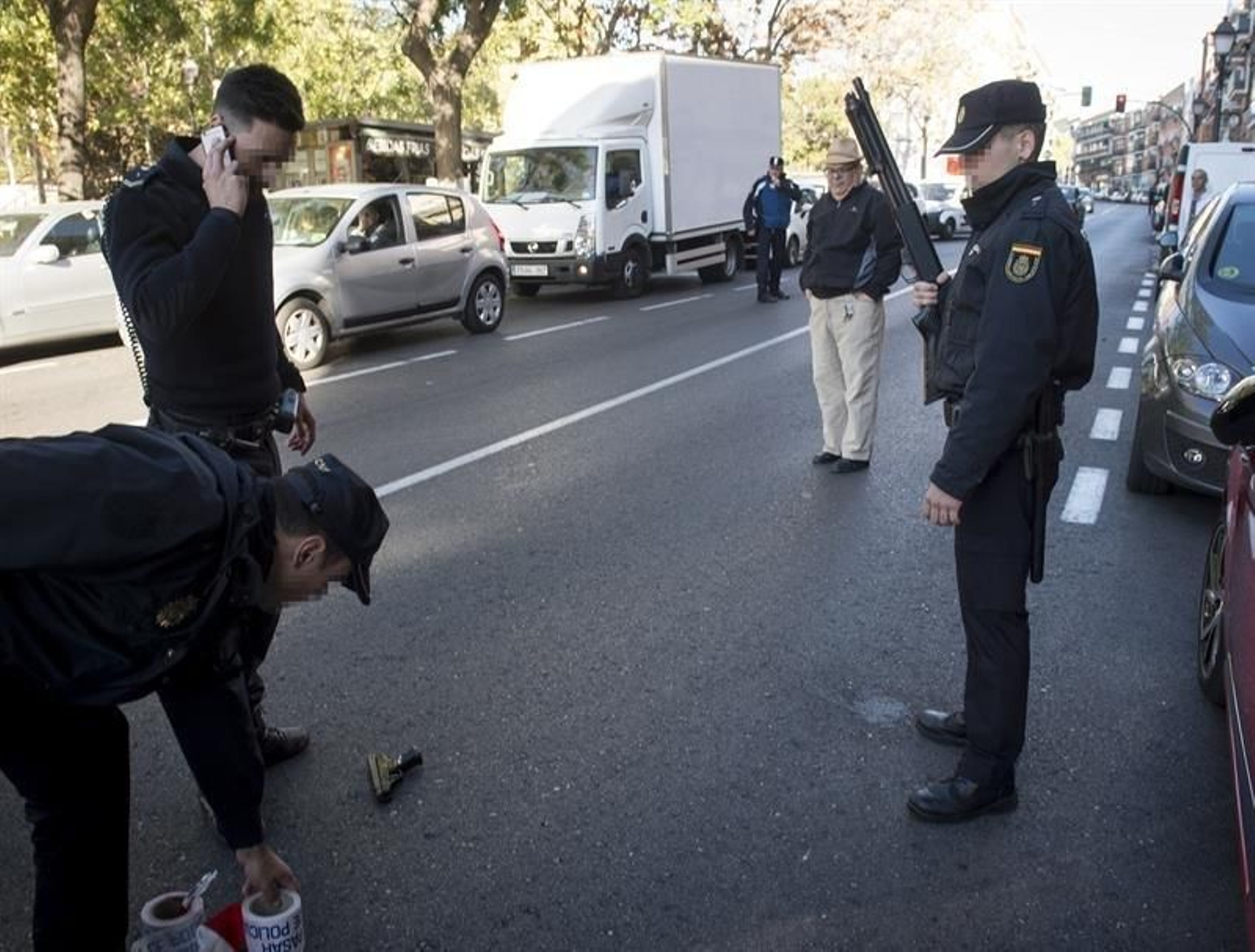 Miembros de la policía nacional custodian la pistola, sobre el asfalto