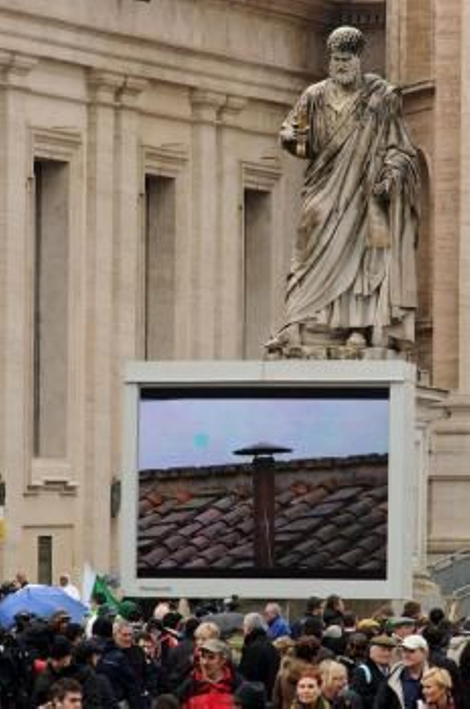 Numerosos fieles desafían el mal tiempo y esperan frente a una de las pantallas el resultado de la segunda fumata