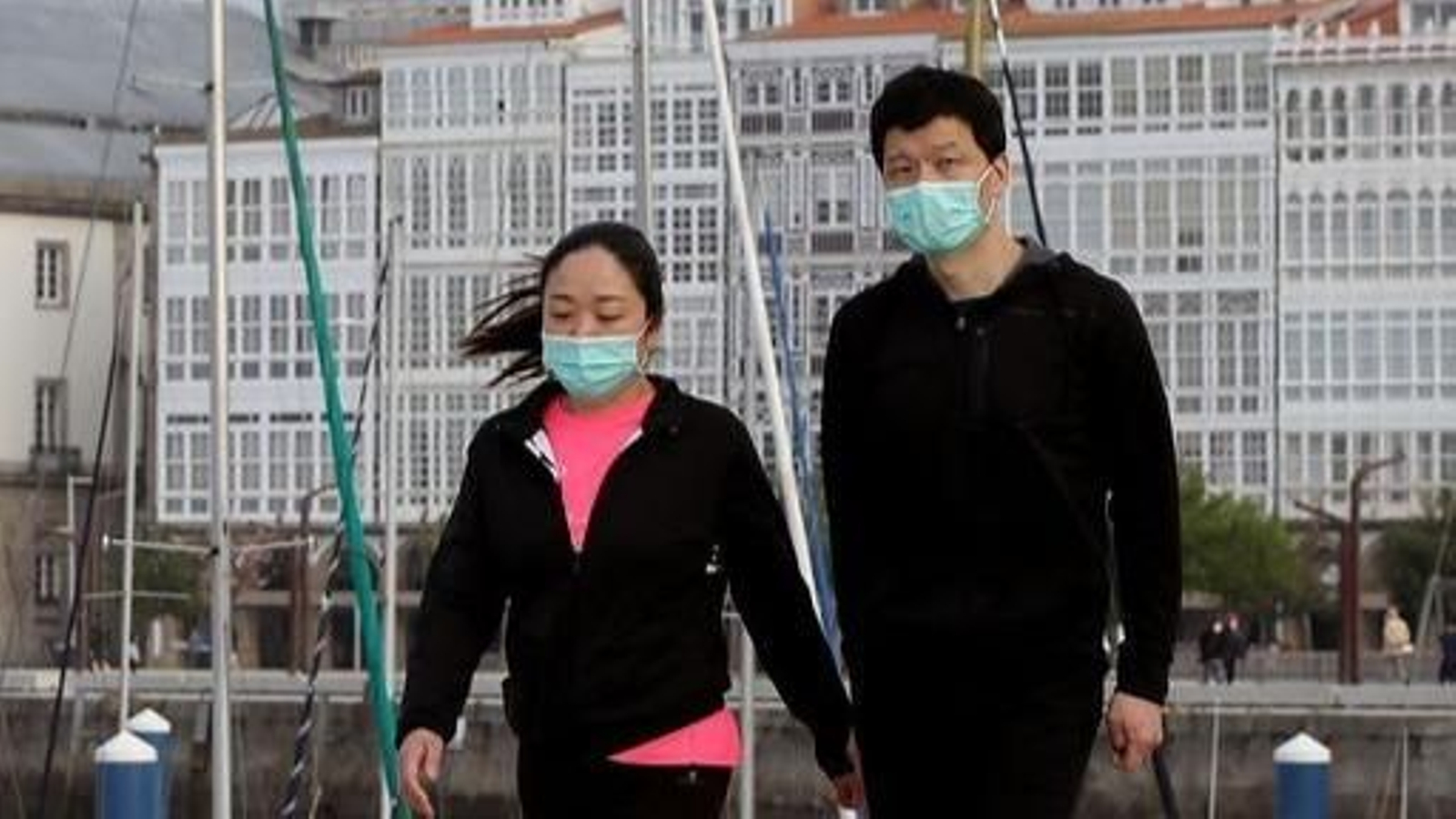 Una pareja pasea por el puerto de A Coruña provista de mascarillas.
