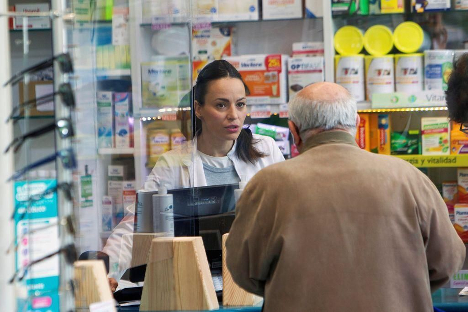 Una farmacéutica atienden a un cliente en una botica de Vigo.