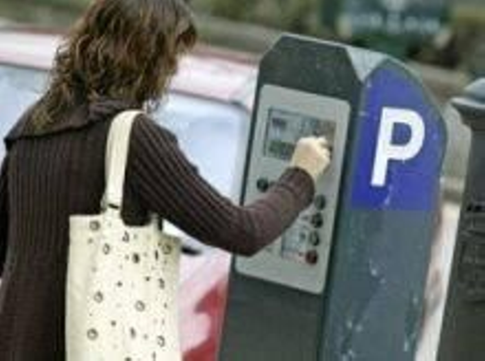 Una mujer saca el ticket que le permitirá estacionar en zona azul.