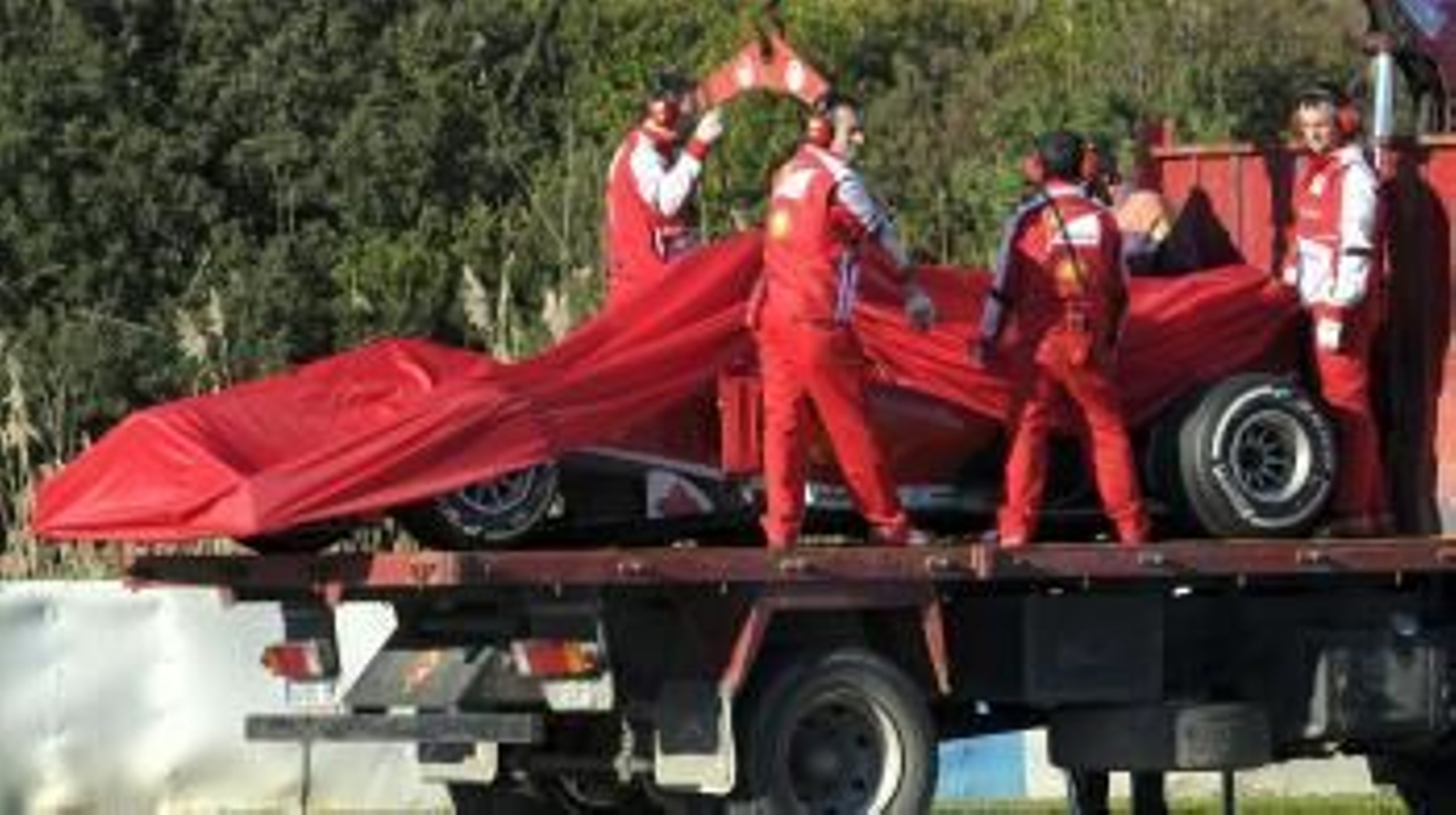 Operarios de Ferrari retiran el monoplaza de Pedro Martínez de la Rosa.