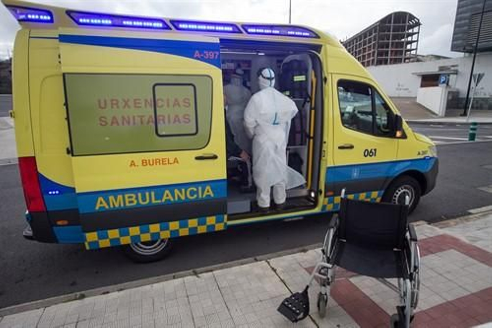 Un trabajador sanitario totalmente protegido ayuda a subir a la ambulancia a un anciano de la residencia de ancianos