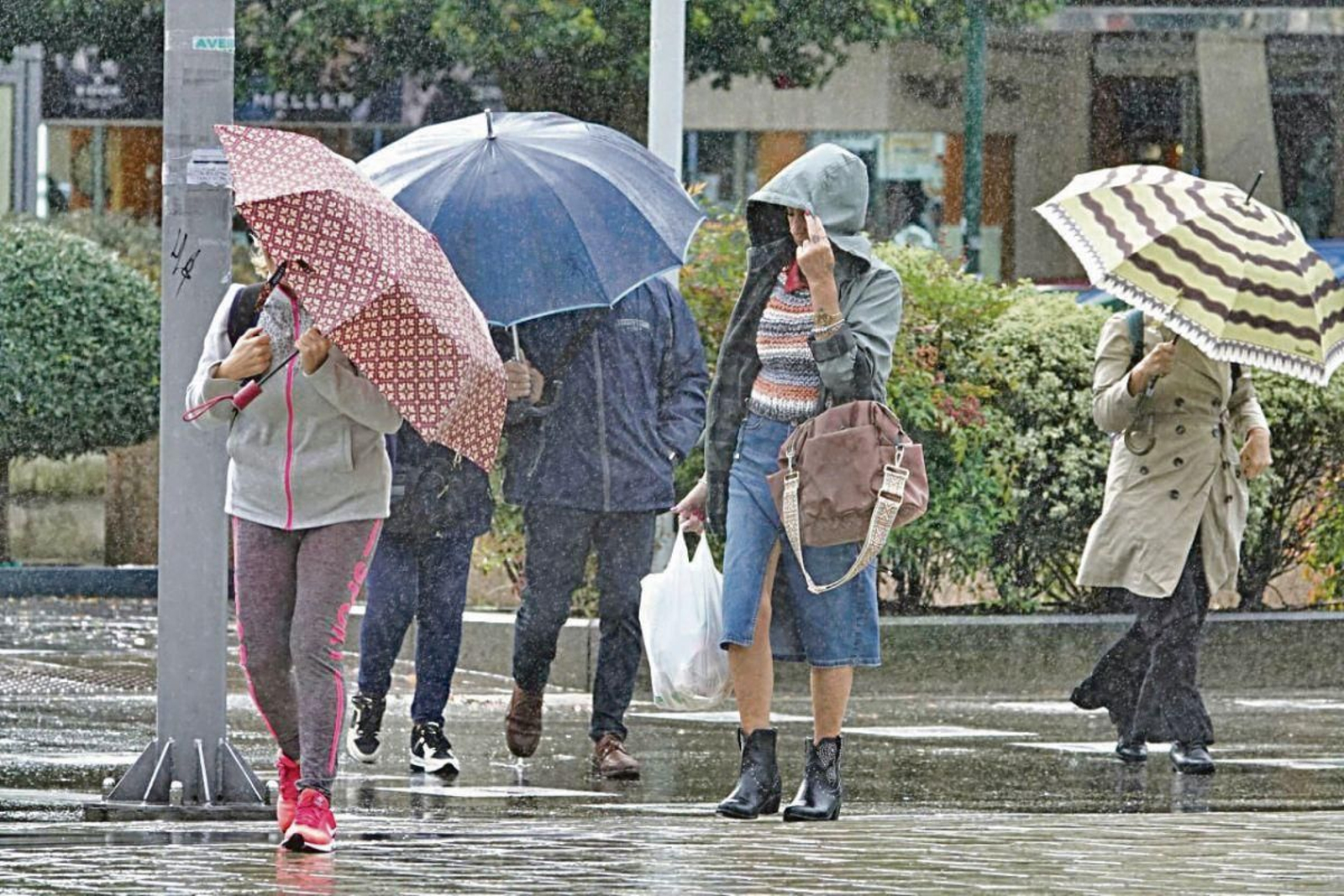 Personas con paragüas en Vigo tratando de paliar los efectos del viento.