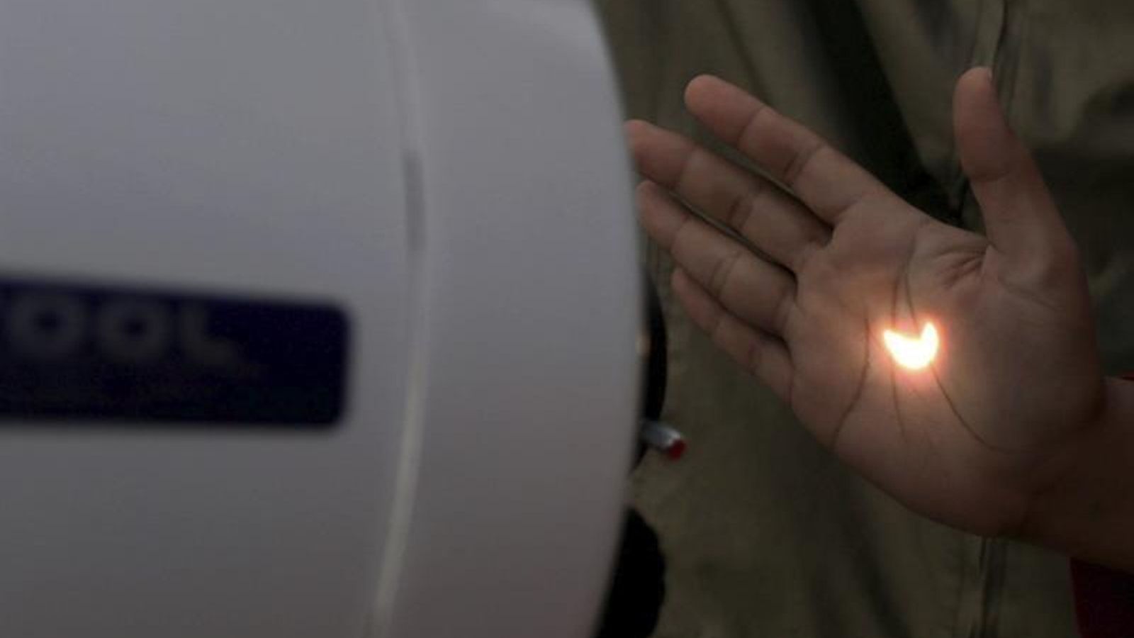 Una joven ve el eclipse reflejado en su mano através de un telescopio en Palembang (Indonesia)