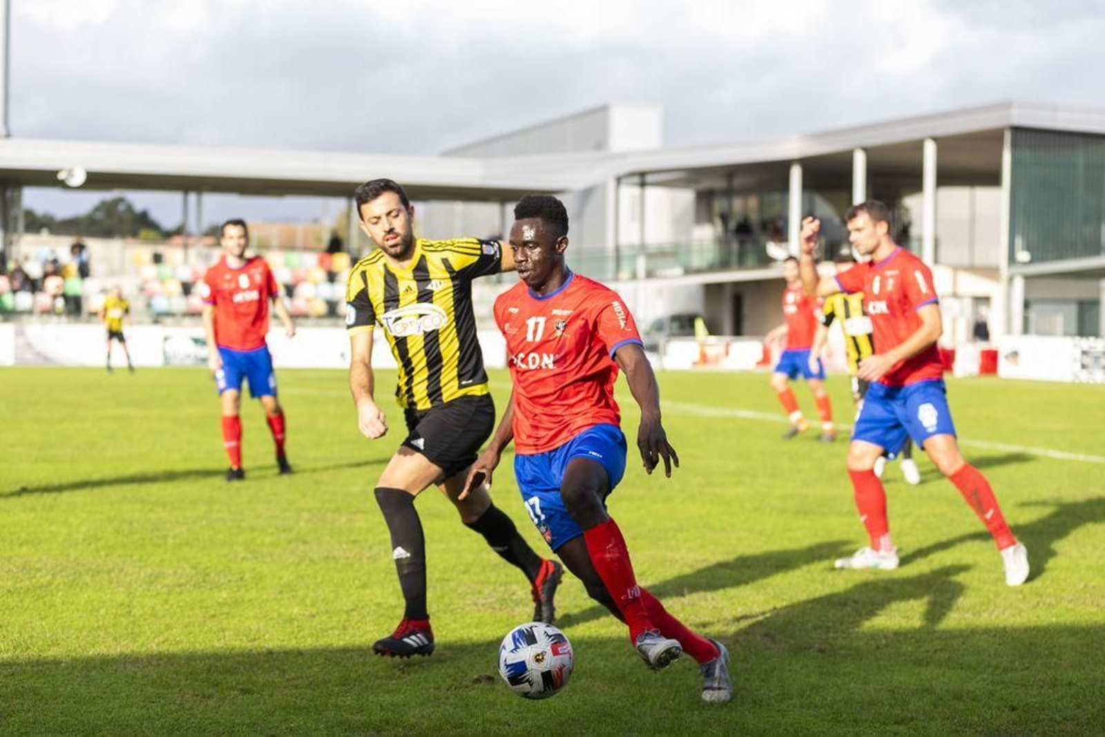 Iano conduce un balón perseguido por un futbolista del Ribadumia.