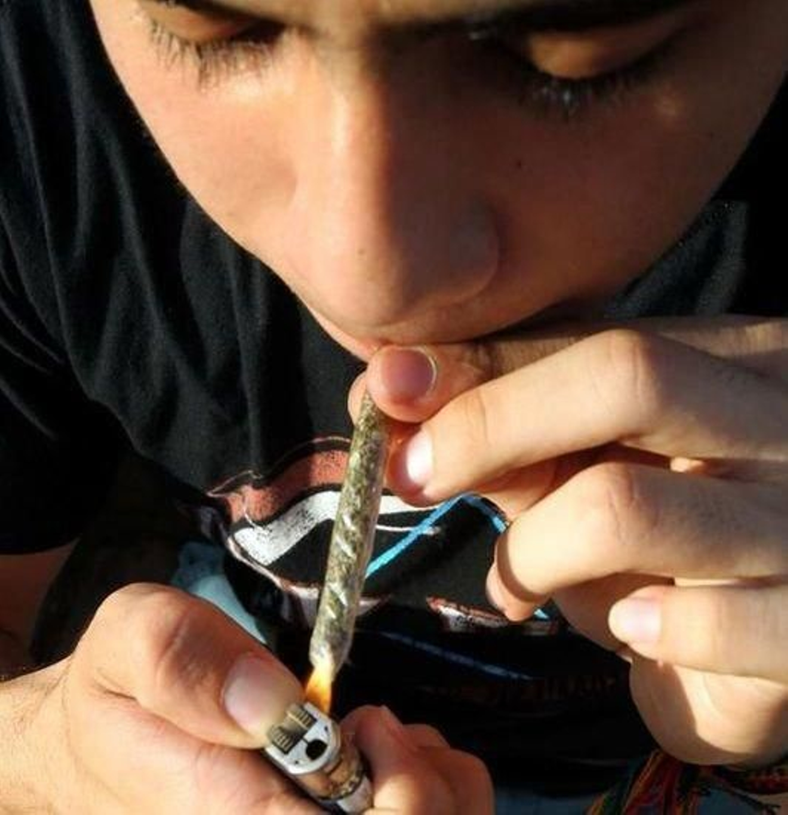 Un joven enciende un porro.