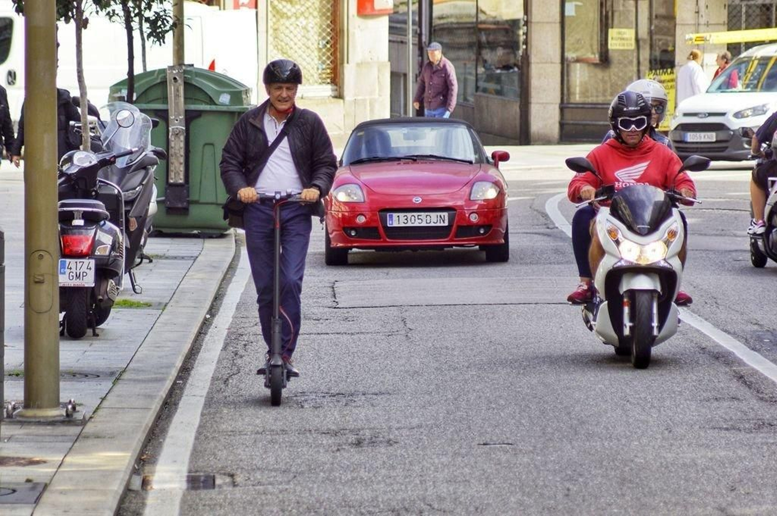 En la imagen tomada ayer en el centro el usuario de patinete lleva casco y circula por la calzada.