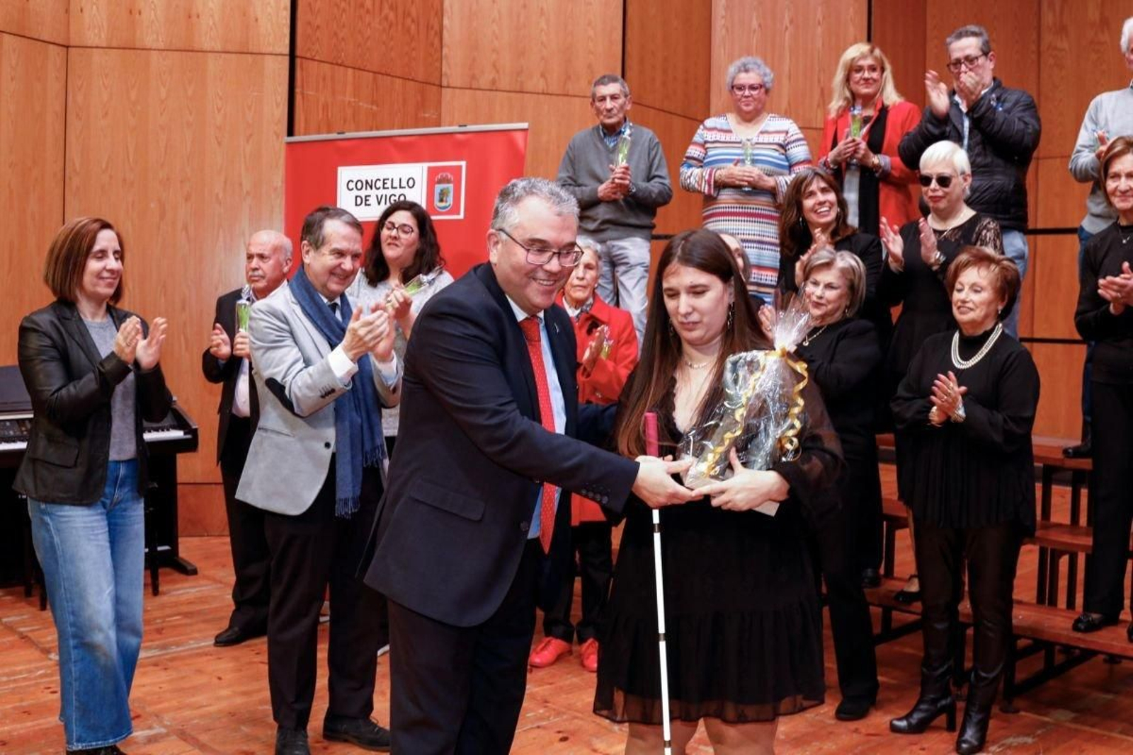 El presidente de Acopovi, Enrique Lorenzo, entrega el premio a la Coral de la ONCE en presencia del alcalde.