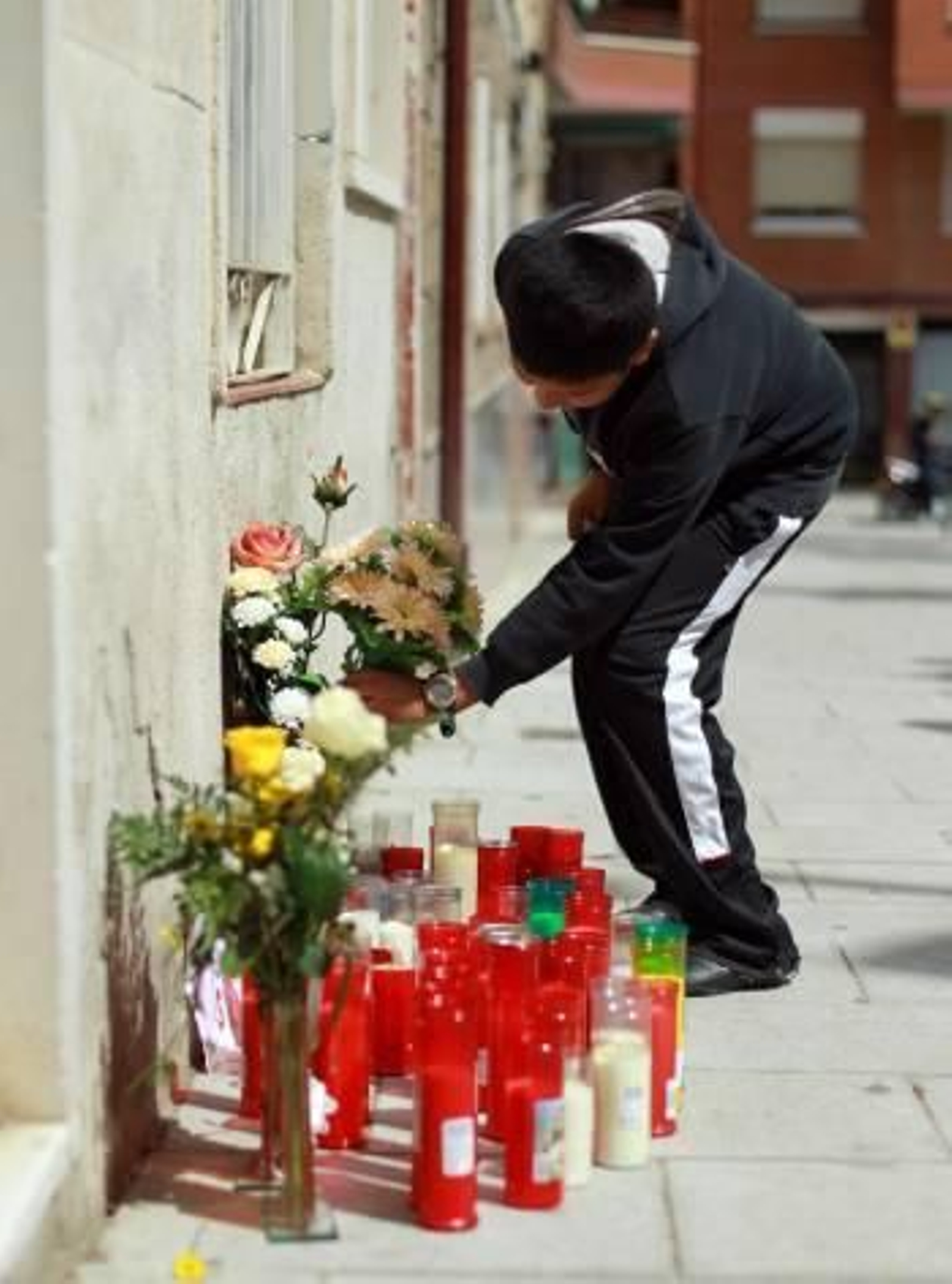 Uno de los vecinos coloca flores y velas en el domicilio de los niños. (Foto: TONI ALBIR)