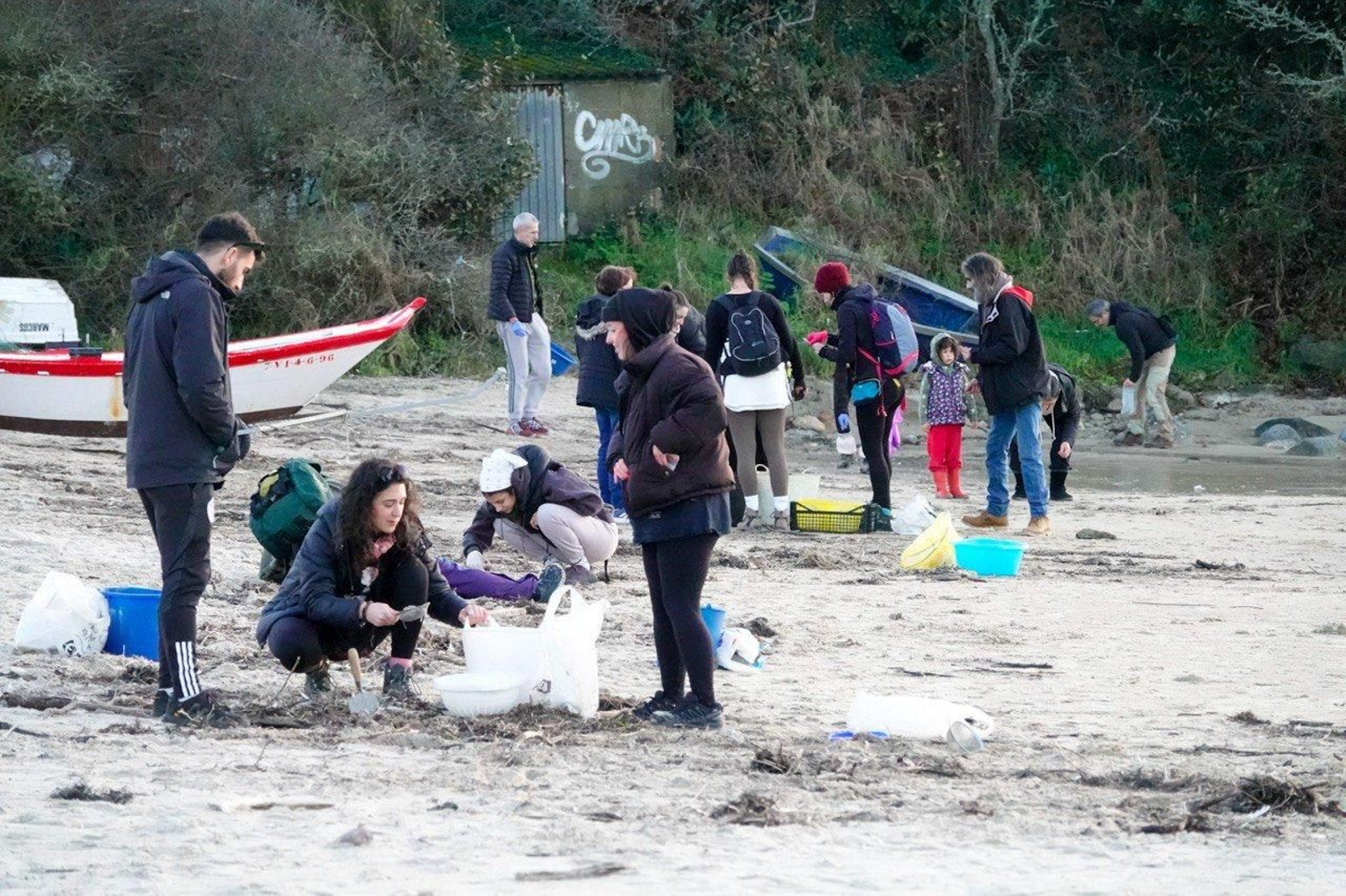 Voluntarios recogen pellets de plástico.