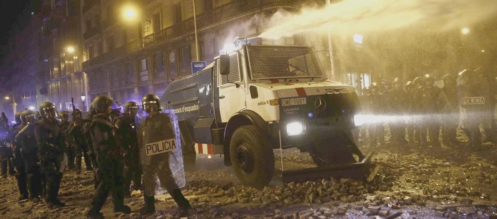 Un grupo de policías antidisturbios junto a la tanqueta de agua a presión