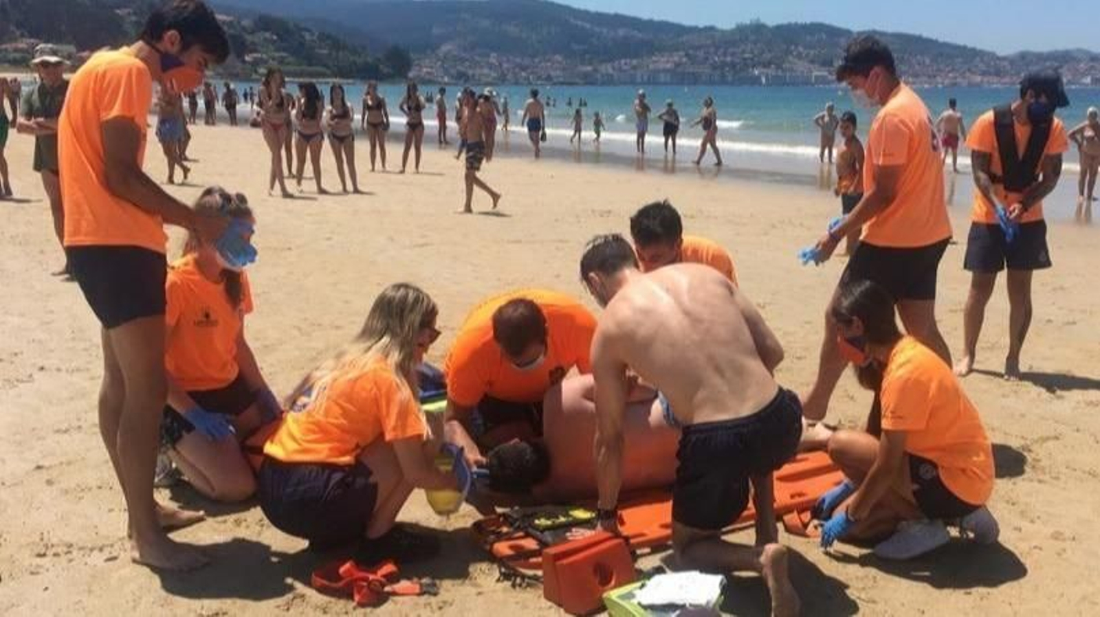 Voluntarios de Protección Civil realizando la simulación de la intervención este lunes en Playa América.