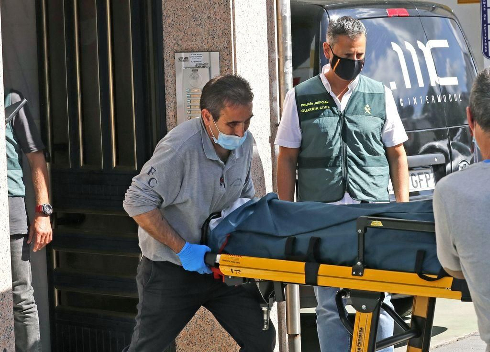 Operarios de una funeraria trasladan el cadáver en presencia de miembros de la Guardia Civil.