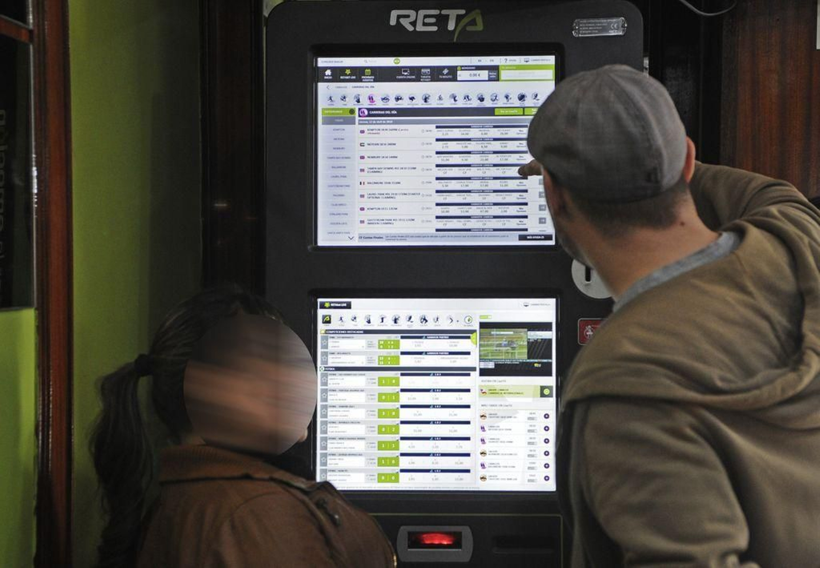 Una pareja de jóvenes junto a una de las populares máquinas de apuestas "online".